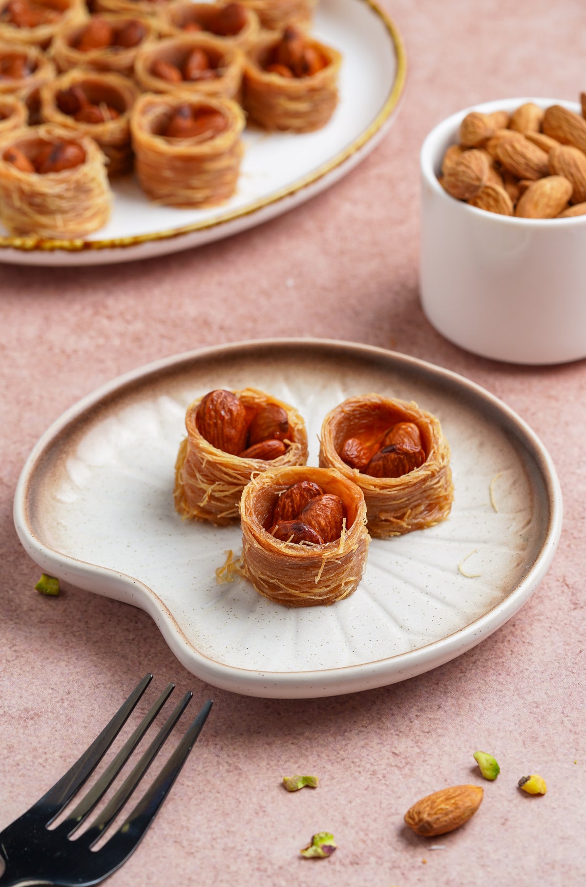Three almond nest baklava pieces on a white plate, close up